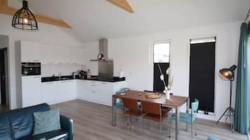 Una cucina moderna con mobili bianchi, un tavolo da pranzo in legno e un divano blu.