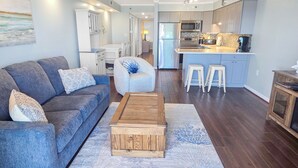 A modern living room with a grey sofa, a wooden coffee table, and a patterned rug.