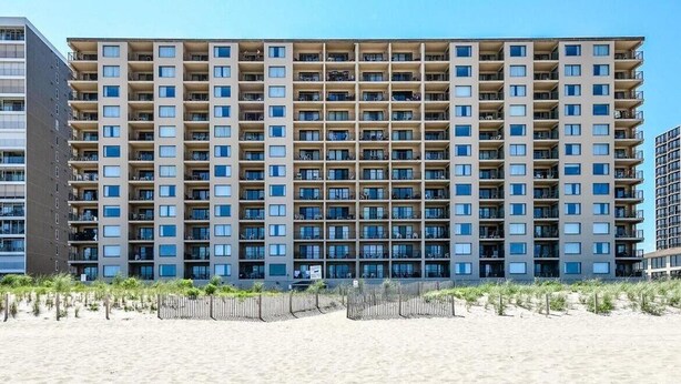 A multi-story hotel with a uniform exterior, located adjacent to a sandy beach.