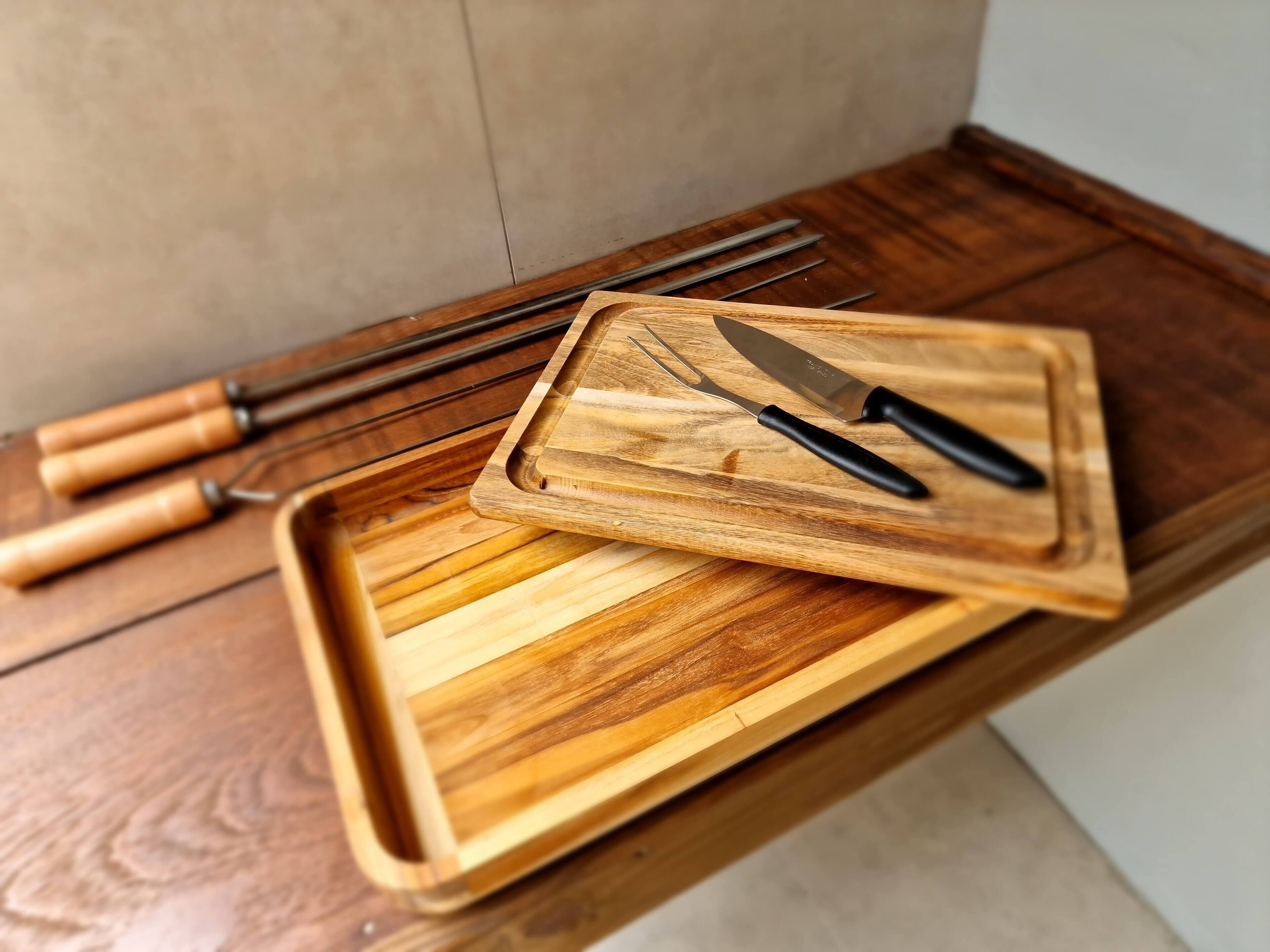 Una bandeja de madera con cuchillos y tenedores sobre una mesa de madera.