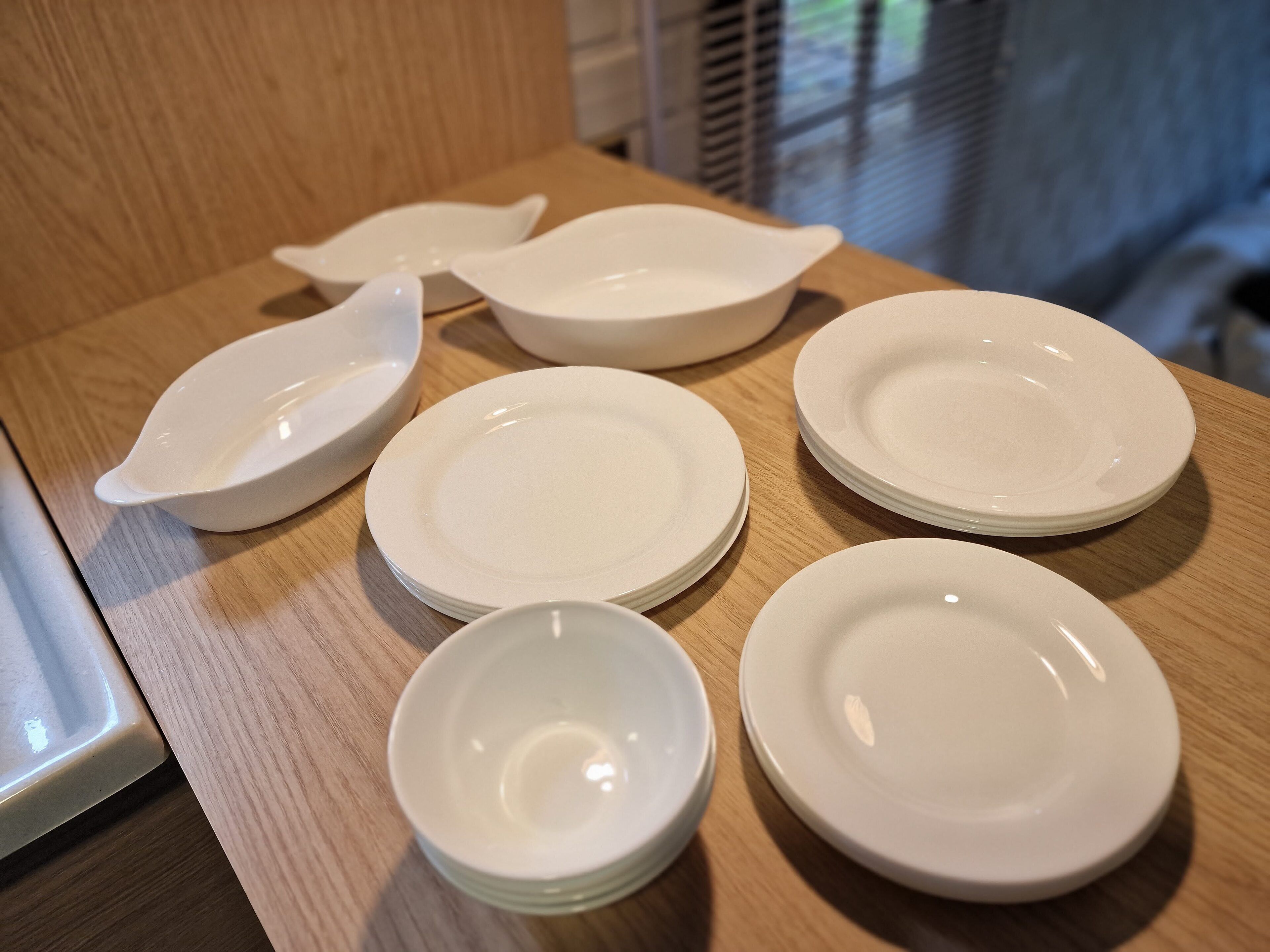 Un ensemble d’assiettes et de bols blancs, posés sur une table en bois.