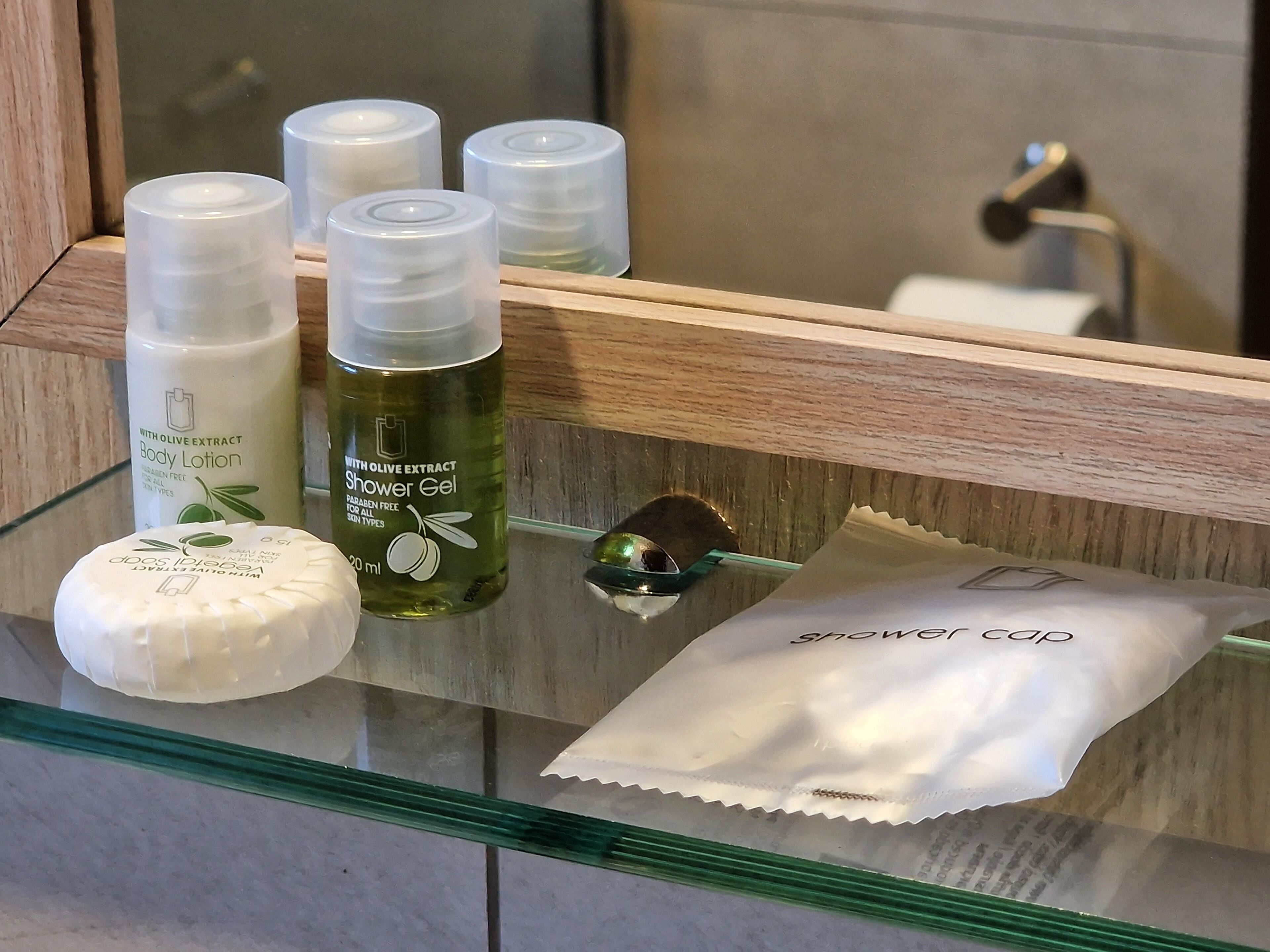 A bathroom shelf with various toiletries including body lotion, shower gel, and a bar of soap.