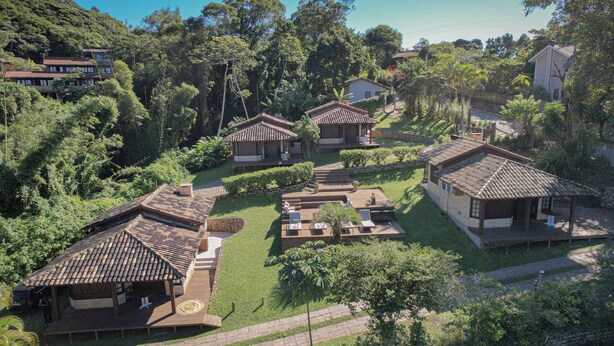 A cluster of traditional-style buildings with tiled roofs, surrounded by lush greenery and a well-maintained lawn. - CalaRosa . Condomínio (Imbituba)