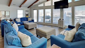 A spacious living room with blue sofas and a large TV. - Bellcove | Waterfront + Boat Dock/Slip (Surf City)