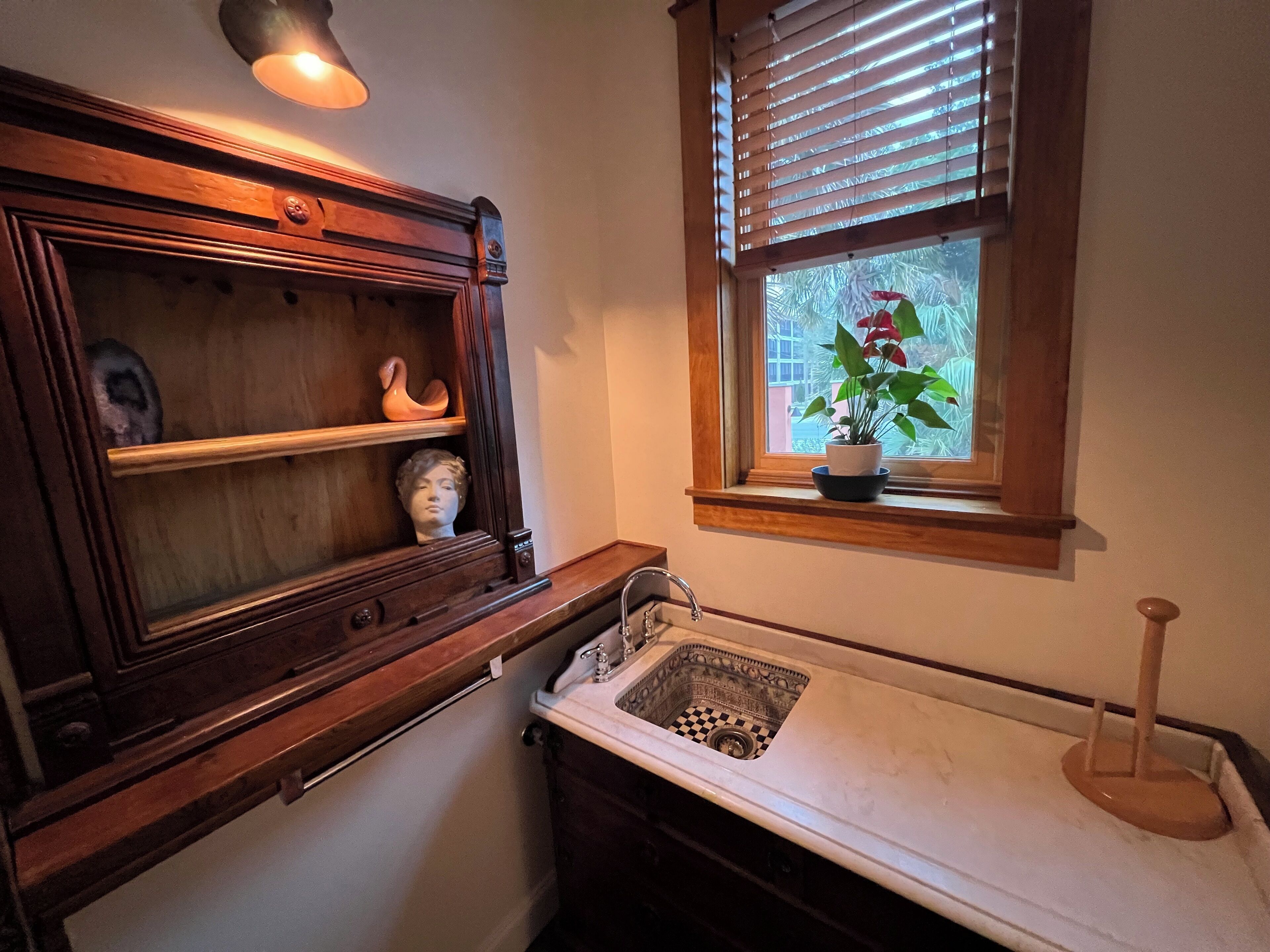 A bathroom with a wooden vanity, a sink with a checkered basin, and a window with blinds.