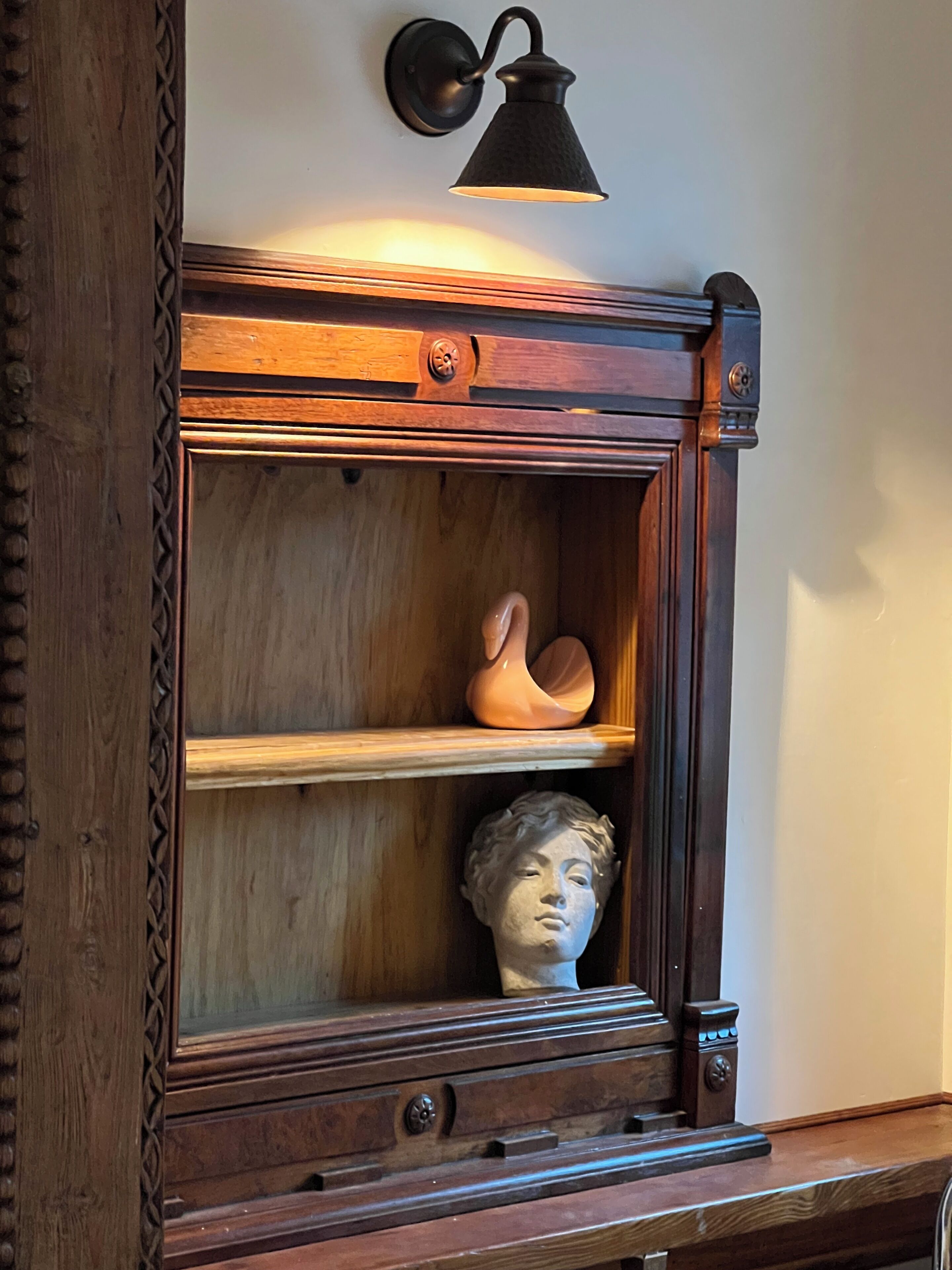 A wooden cabinet with a wall-mounted light fixture above it.