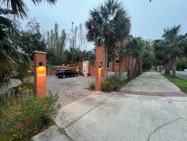 A paved driveway leading to a building with a black SUV parked in front.