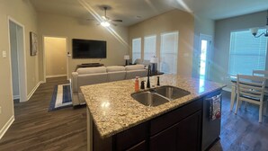 A modern kitchen with granite countertops, a double sink, and a ceiling fan. - Houma Way From Home with Arcade & EV Charger (Houma)