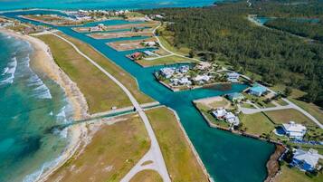 An aerial view of a coastal property with a marina, houses, and a forested area.