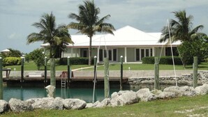 En ejendom ved stranden med pool, palmer og en hvid bygning.