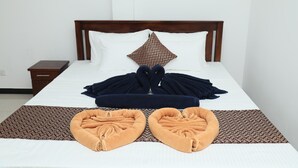 A neatly made bed with a patterned throw blanket, a decorative pillow, and two heart-shaped towels on a patterned bedspread. - crystal wave (Matara)