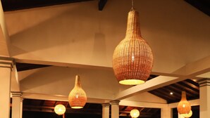 A spacious dining area with wooden tables and chairs, large windows, and hanging wicker lamps. - crystal wave (Matara)