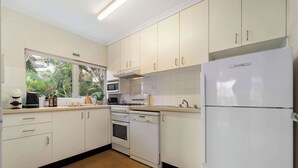 Une cuisine avec des meubles blancs, un réfrigérateur, une cuisinière et un four à micro-ondes.
