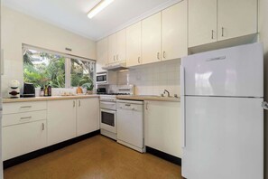 A kitchen with white cabinets, a refrigerator, a stove, and a microwave.