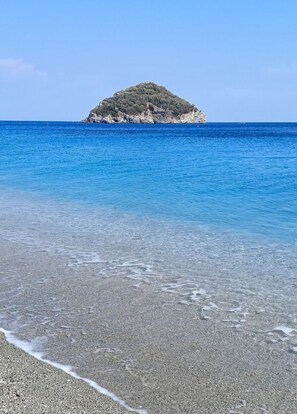 A beach with clear water and a small island in the distance. - Sundevilla Designer Penthouse with a terrace overlooking the ocean, parking, and a pool (Bergeggi)