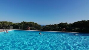 A clear blue pool with a view of the ocean and trees in the background. - The Sundevilla Designer Penthouse with sea view terrace, parking space and pool (Bergeggi)