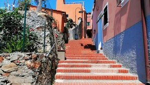 A set of red brick stairs leading up a stone wall, flanked by buildings with balconies and windows. - The Sundevilla Designer Penthouse with sea view terrace, parking space and pool (Bergeggi)