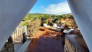 A patio with outdoor furniture and a view of a hilly landscape.