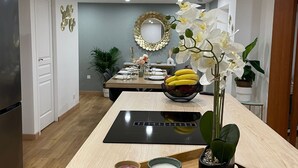 A modern kitchen with a central island, a refrigerator, and a dining area with a table set for two. - Parifou Air-conditioned cosy house with play area for families (Riom)