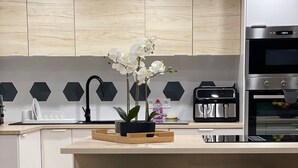 A modern kitchen with a central island, bar stools, a sink, and a built-in oven. - Parifou Air-conditioned cosy house with play area for families (Riom)