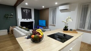 A modern kitchen with a central island, a dining area with a sofa, and a fireplace. - Parifou Air-conditioned cosy house with play area for families (Riom)