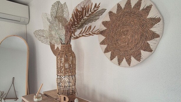 Una mesa de madera con una cesta tejida y un adorno con la palabra 'Bonjour'.