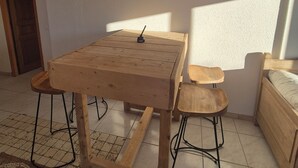 Una habitación con una mesa de madera y dos taburetes, una decoración de cabeza de toro en la pared y una cama.