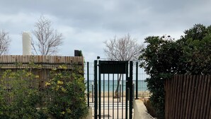 A gated entrance with a gravel path leading to a beach.