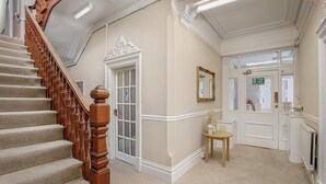 A staircase with a wooden handrail leading to a door with a glass panel. - Hotel Sofia (Blackpool)