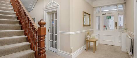 A staircase with a wooden handrail leading to a door with a glass panel.