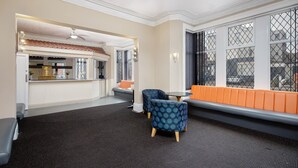 A modern interior with a seating area, a bar, and a view through large windows. - Hotel Sofia (Blackpool)