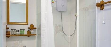 A bathroom with a shower enclosure, a sink, a toilet, and a mirror.