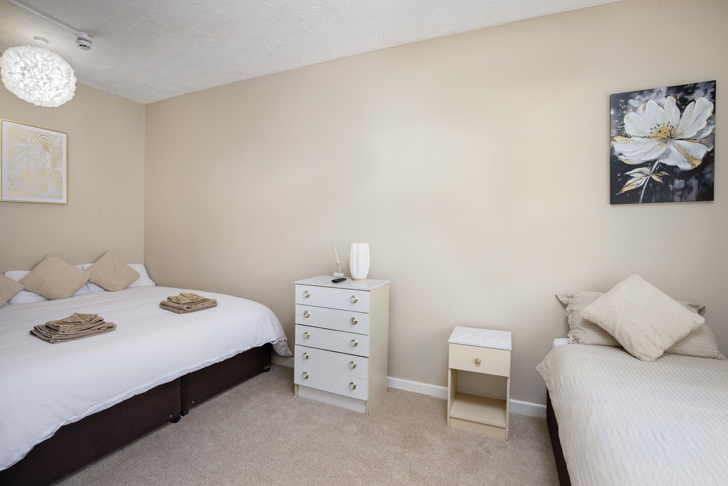 Une chambre à coucher avec un lit, une commode, une table de chevet et un tableau accroché au mur.