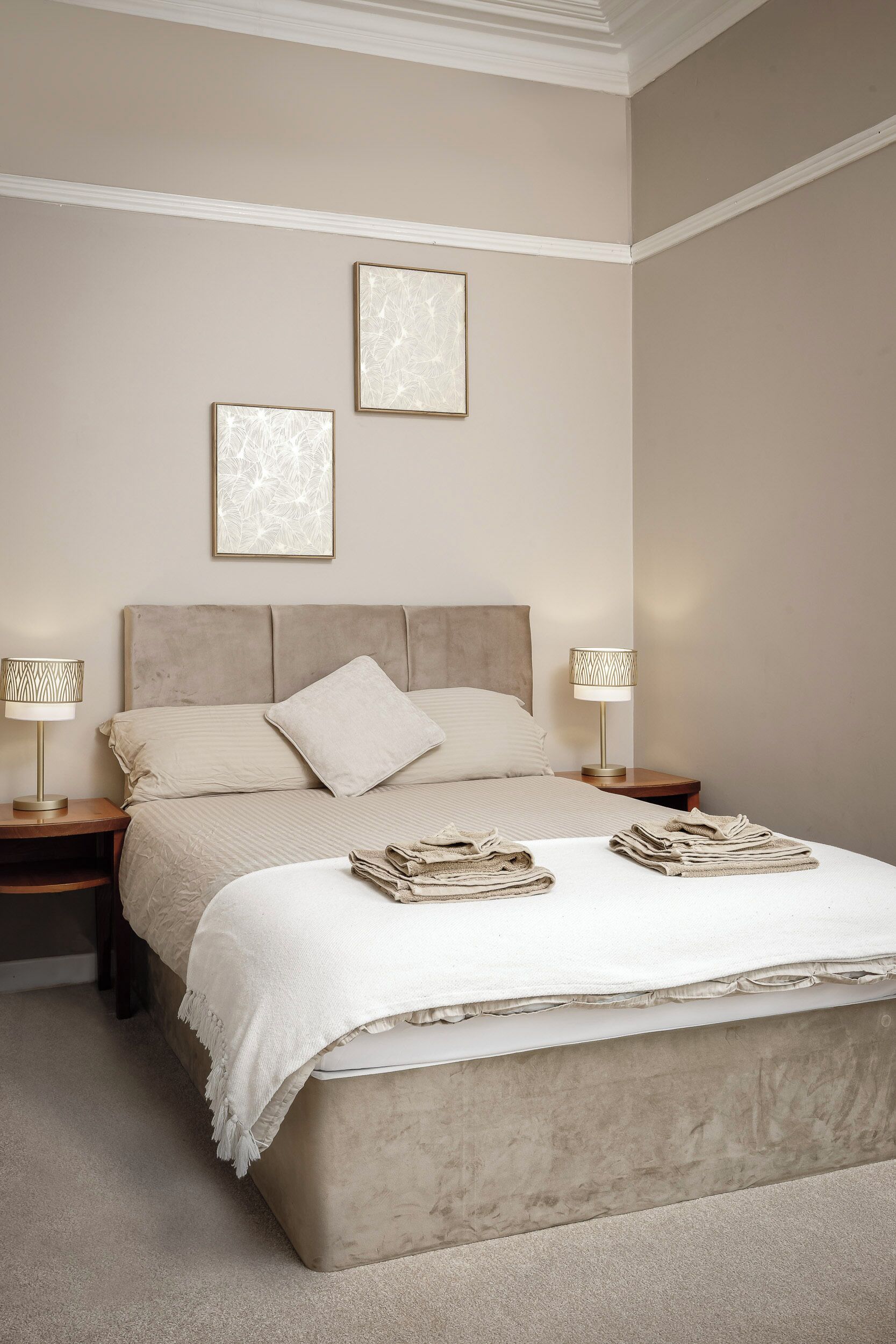 A neatly arranged bedroom with a large bed, two bedside tables, and two wall-mounted lamps.