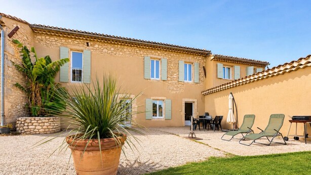 A building with a courtyard, outdoor seating, and a large potted plant. - MAS DE LA BERRE SOUTH DROME AND GATEWAY TO ARDECHE, VAUCLUSE AND GARD (Donzère)