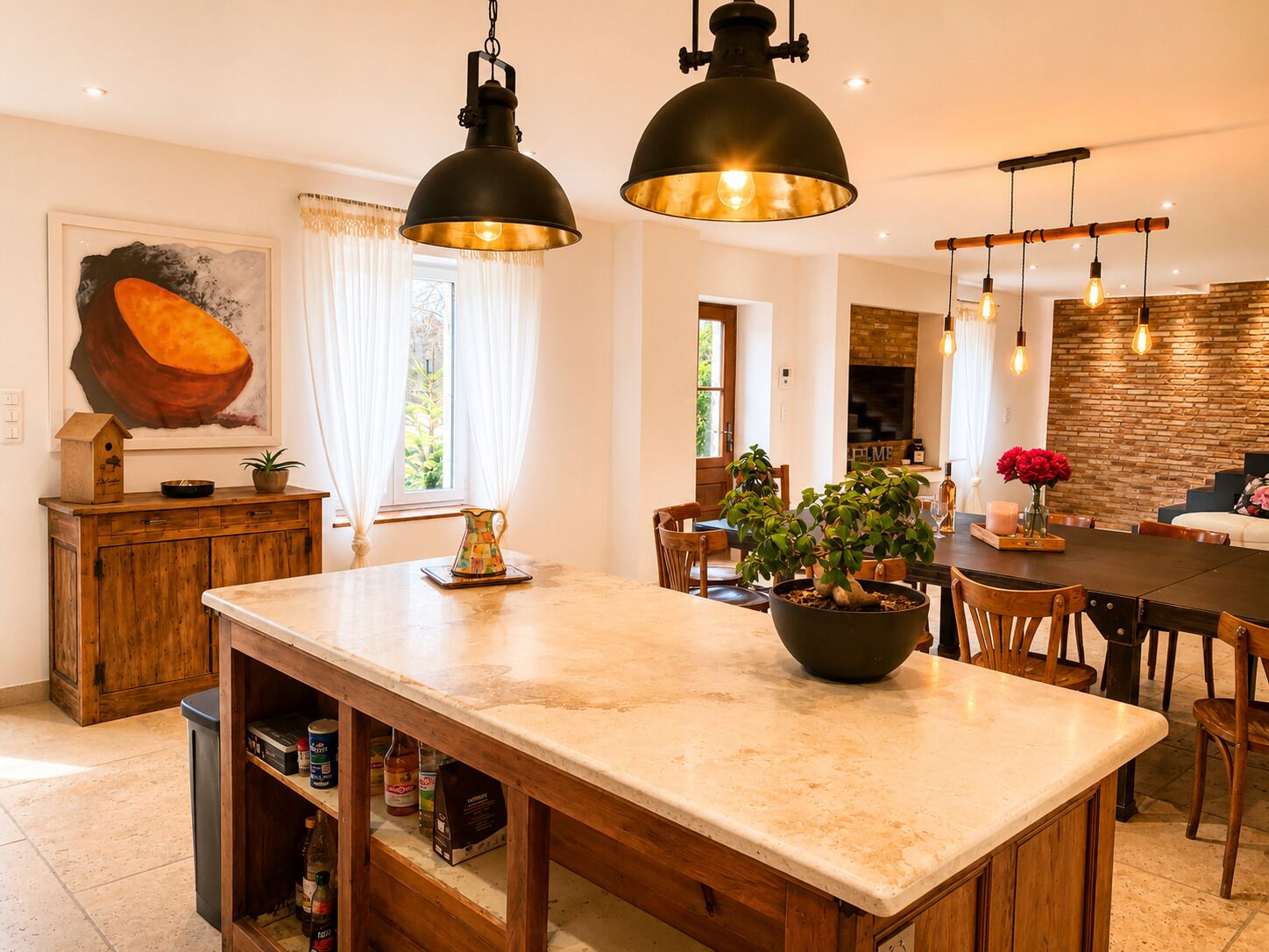 Een keuken met een centraal eiland, houten kasten, hanglampen en een bakstenen muur.