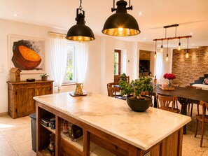 A kitchen with a central island, wooden cabinetry, pendant lighting, and a brick wall. - MAS DE LA BERRE: SOUTHERN DROME AND GATEWAY TO THE ARDÈCHE, VAUCLUSE, AND GARD (Donzère)