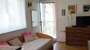 Une chambre à coucher comprenant un lit, une commode, un téléviseur et une fenêtre donnant sur un paysage verdoyant.