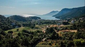 Un paysage côtier offrant une vue dégagée sur la mer, les collines et quelques bâtiments dispersés.