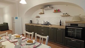 A modern kitchen with a dining table set for two, featuring a white tablecloth and a floral placemat. - Apartment in the heart of the Amalfi Coast (Praiano)