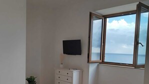 A bedroom with a bed, a dresser, a TV, and a window with a view of the sea. - Apartment in the heart of the Amalfi Coast (Praiano)