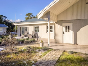 A modern house with a covered patio, a door, and a small garden area.