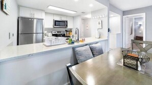 Une cuisine moderne avec des armoires blanches, des appareils en acier inoxydable et un îlot central.