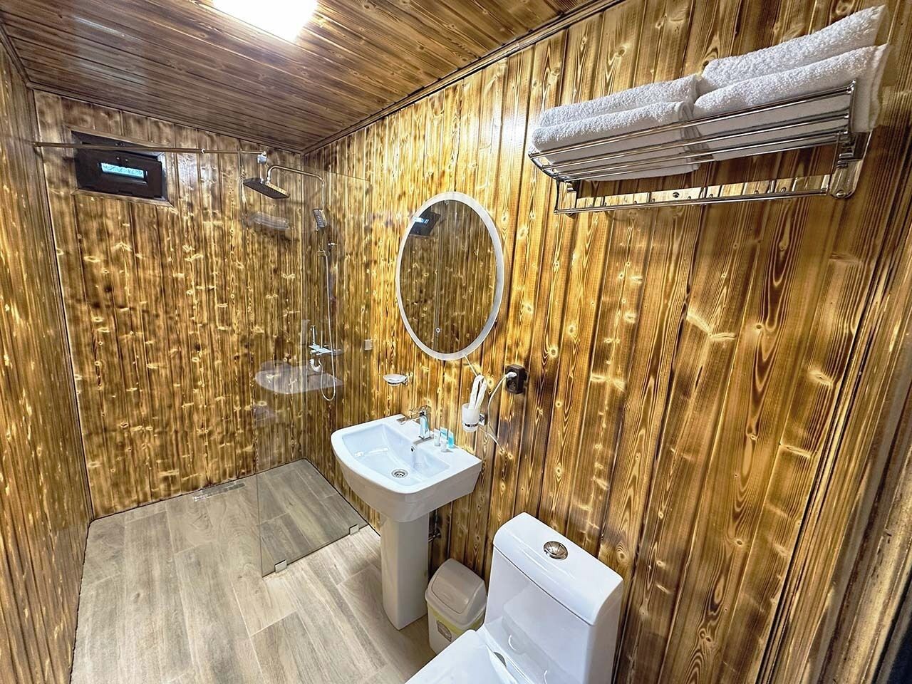 Un baño con paneles de madera, un lavabo, un inodoro y una ducha.