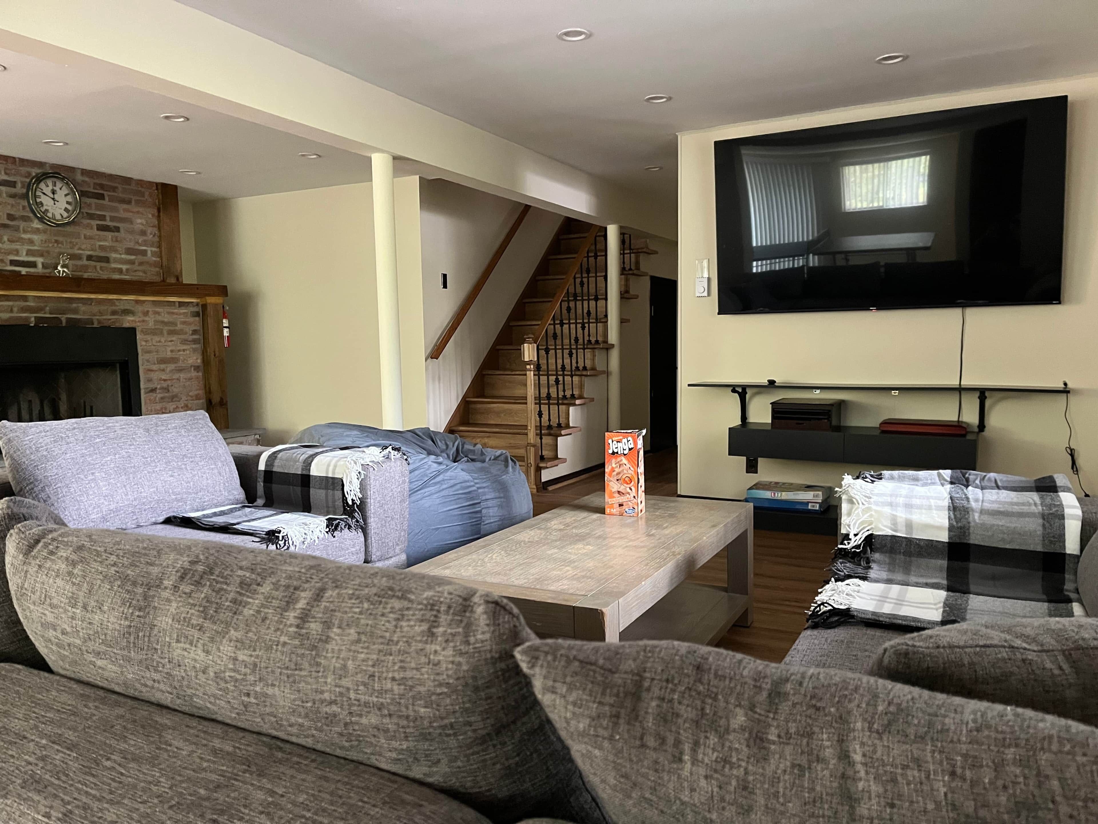 A living room with a sofa, a coffee table, a fireplace, a TV, and a staircase.