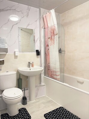 A bathroom with a toilet, sink, and shower. - Rivington View Apartment (Dagenham)