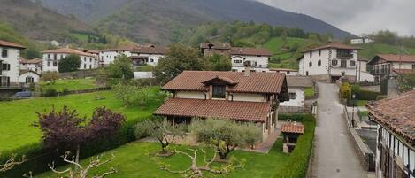 A hillside village with traditional white buildings, a central road, and lush greenery.