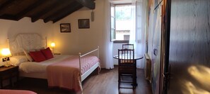 A bedroom with a bed, bedside lamps, a chair, a window, and a door. - Hostal Mendaurpe (Ituren)