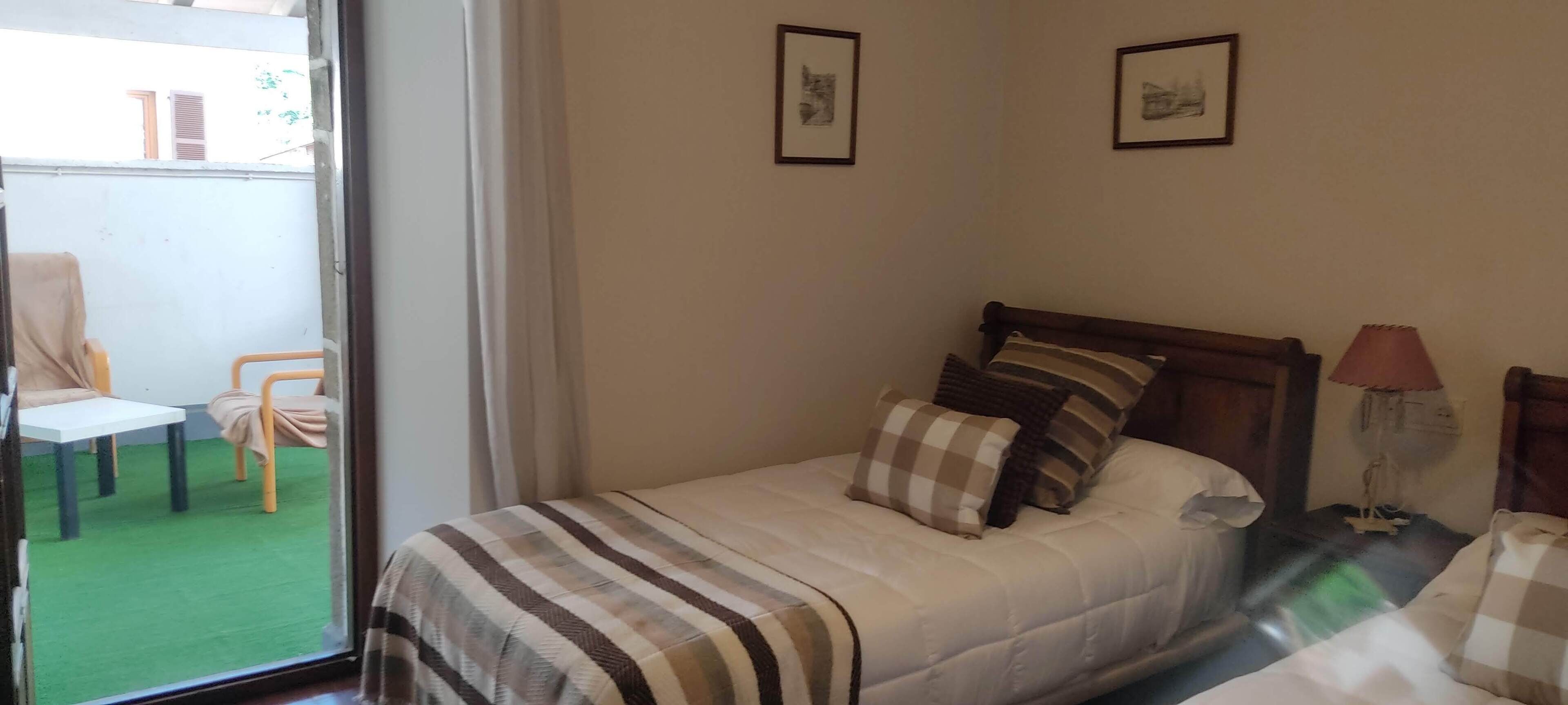 Une chambre à coucher avec un lit, une table de chevet, une lampe et deux tableaux encadrés accrochés au mur.