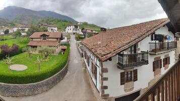 Un pueblo tradicional con edificios de piedra, una calle empedrada en el centro y un parque verde y exuberante.